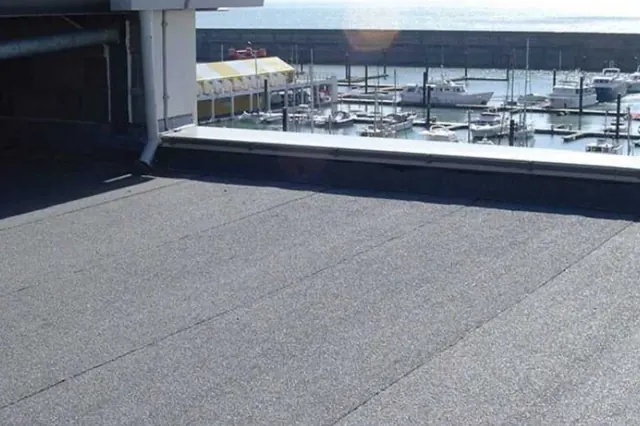 Bitumen langs een glazen pui — Bitumineuze dakbanen met een aansluiting langs een glazen pui.