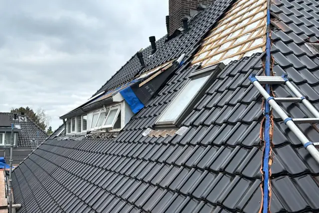 Pannendak tijdens vernieuwing — Een deel van het dak is gedekt; hoger op het dak zijn de panlatten nog zichtbaar.